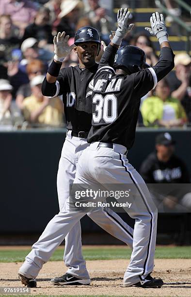 Alexei Ramirez and Alejandro De Aza of the Chicago White Sox celebrate at home plate after scoring during a spring training game against the Oakland...