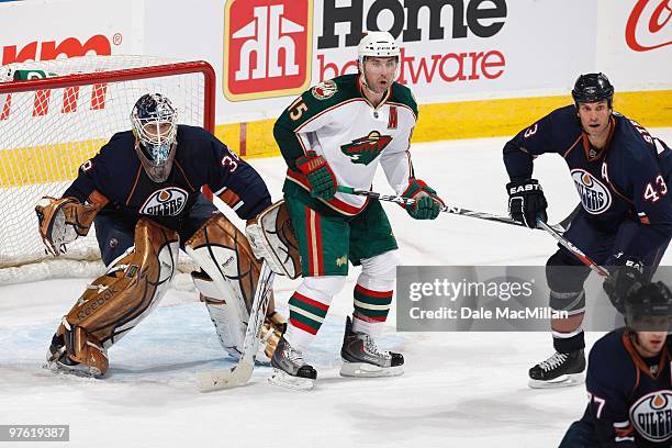 Andrew Brunette of the Minnesota Wild moves into position against Jason Strudwick and goalie Jeff Deslauriers of the Edmonton Oilers on March 5, 2010...