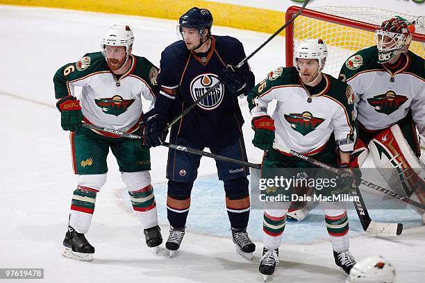 Robert Nilsson of the Edmonton Oilers is guarded by Greg Zanon and Andrew Ebbett of the Minnesota Wild on March 5, 2010 at Rexall Place in Edmonton,...