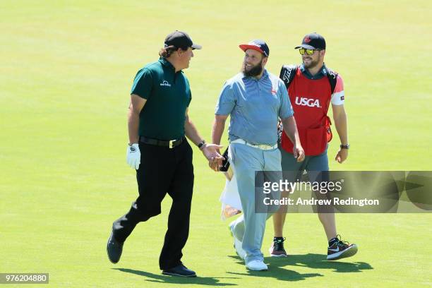 Phil Mickelson of the United States, Andrew 'Beef' Johnston of England, and caddie Will Davidson walk on the first green during the third round of...
