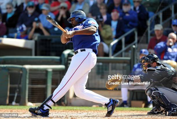 Vladimir Guerrero of the Texas Rangers bats as Adam Moore of the Seattle Mariners catches during a spring training game against the Seattle Mariners...