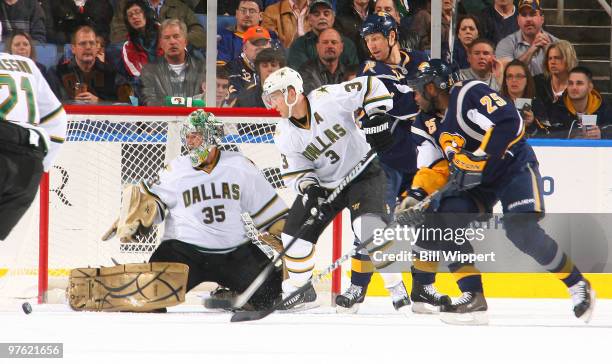 Michael Grier and Adam Mair of the Buffalo Sabres keep an eye on the puck as Marty Turco of the Dallas Stars makes a second-period save in front of...