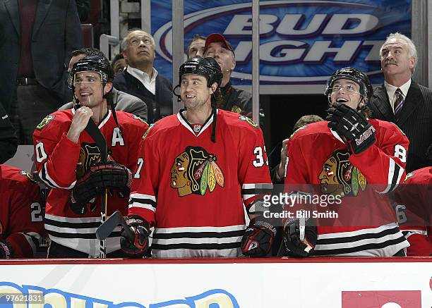 Patrick Sharp, Adam Burish and Patrick Kane of the Chicago Blackhawks watch the video board in front of Blackhawks head coach Joel Quenneville during...