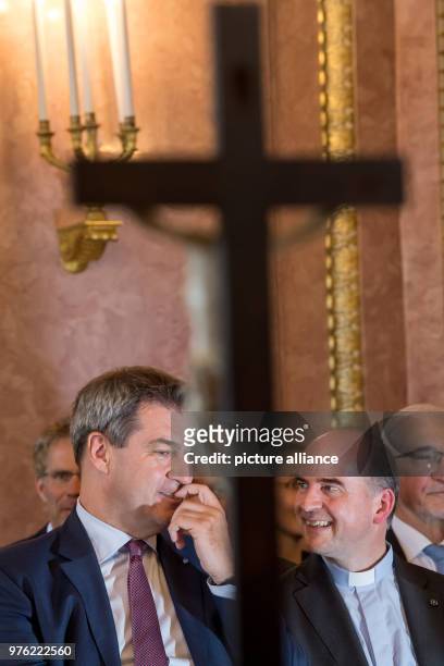 June 2018, Germany, Munich: Markus Söder , Premier of Bavaria, sitting with the freshly sworn-in 89th bishop of Wuerzburg, Franz Jung, behind a cross...