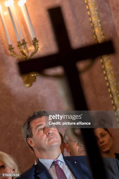 June 2018, Germany, Munich: Markus Soeder , Premier of Bavaria, sitting behind a cross during the swearing-in ceremony of the 89th bishop of...