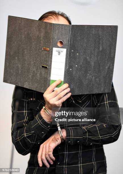 June 2018, Germany, Freiburg: The defendant Juergen W. Of Switzerland covering his face with a folder in the hall of the district court. The...