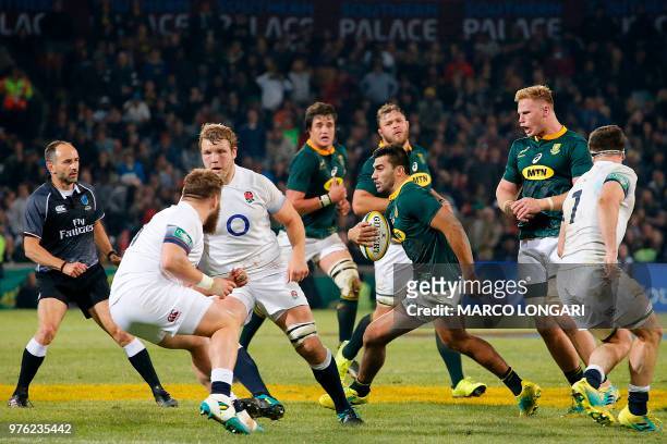 South Africa's centre Damian de Allende runs with the ball as French referee Romain Poite looks on during the second test match South Africa vs...