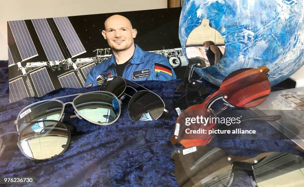 June 2018, Germany, Kuenzelsau: A photograph of the German astronaut Alexander Gerst is displayed beside sunglasses in the shop window of an optician...