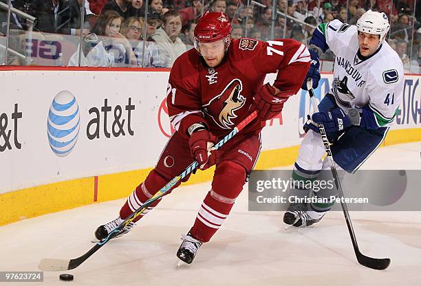 Petteri Nokelainen of the Phoenix Coyotes skates with the puck past Andrew Alberts of the Vancouver Canucks during the second period of the NHL game...