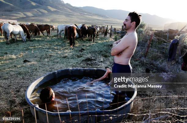 Wranglers cool off and wash off the days dirt in a cold horse trough at camp on June 12, 2018 in Reno, Nevada. The Reno Rodeo Cattle Drive celebrates...