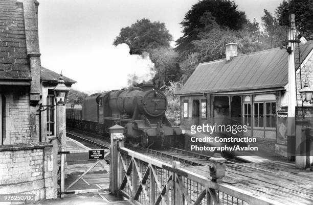 Ketton and Collyweston station in Rutland, England's smallest county. A Stanier 8F steams through with a rake of freight empties, circa 1960.