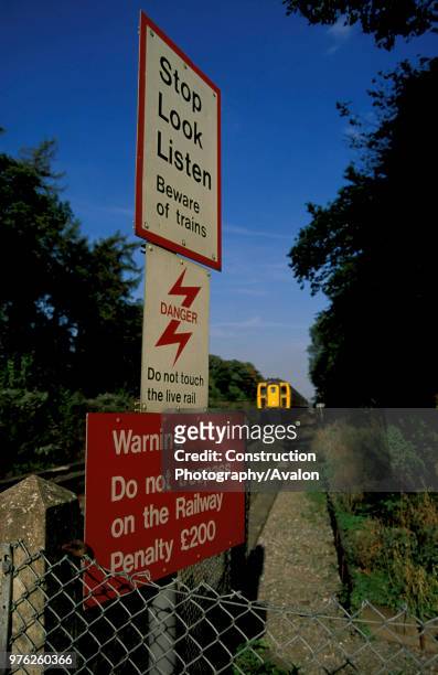 Warning signs at a foot crossing near Basingstoke, Hampshire as a train approaches at speed, circa 1995.
