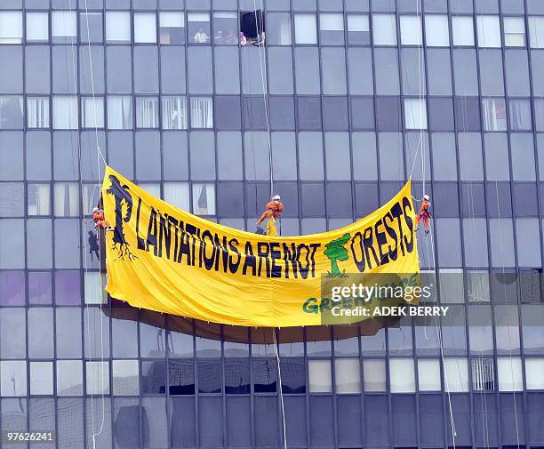 Indonesian Greenpeace activists hang a giant protest banner on the side of the forestry ministry office building in Jakarta on March 11, 2010. Scores...