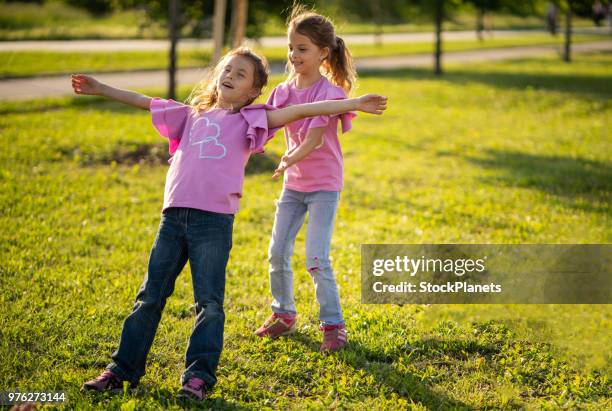 dos hermanas gemelas jugando en la naturaleza - trust fotografías e imágenes de stock