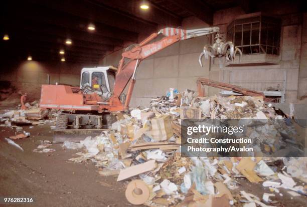 Wheeled digger grabbing rubbish on a refuse centre, Austria.