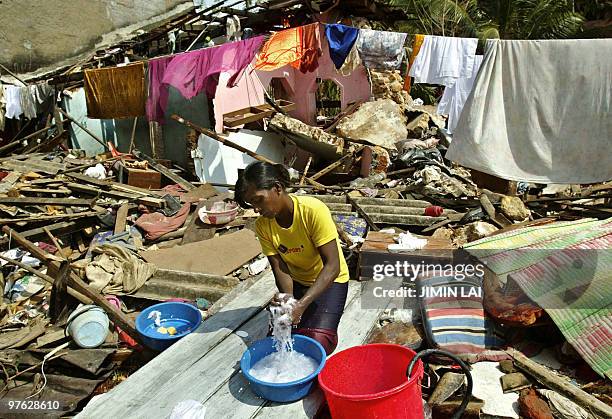 Sri Lankan woman washes clothes in the wreckage of her home which was destroyed during the recent tsunami disaster in the southern coastal town of...