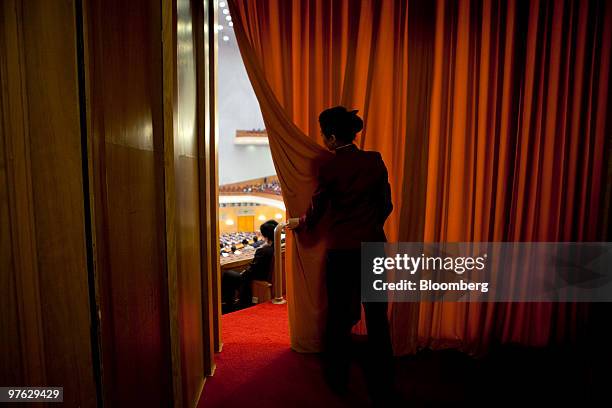 An attendant adjusts a curtain during a plenary session at China's National People's Congress at the Great Hall of the People in Beijing, China, on...