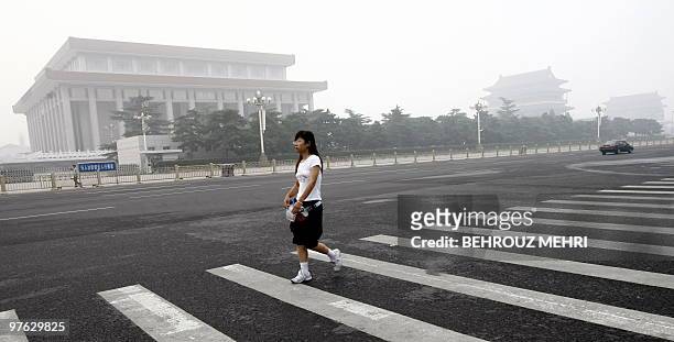 Chinese woman crosses a street passing the Communist Party headquarters near Tiananmen Square in Beijing on August 8, 2008 on the morning of the...