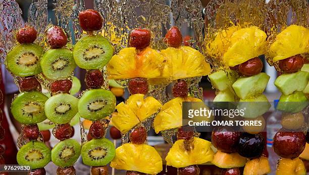 Different types of fruits coated with melted sugar are pictured at a street market close to Wang Fujing street in Beijing on August 07, 2008. The...