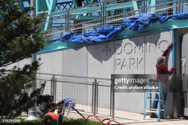 May 2018, USA, New York: A man working on lettering at the entrance to the newly built Domino Park in Brooklyn. A sugar refinery had stood on the...