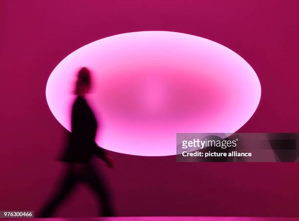 June 2018, Baden-Baden, Germany: A person walks past the light installation " Healing Light, Curved Elliptical Glass of the year 2018" by the...