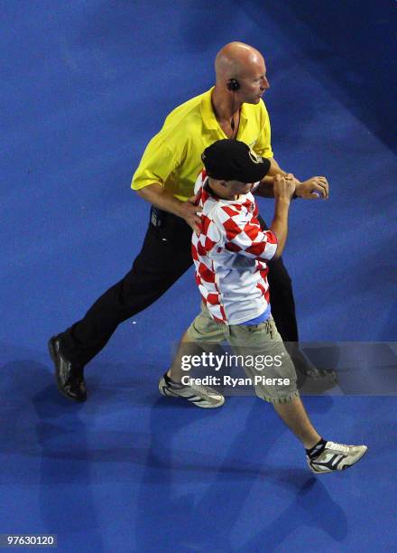 Spectator is escorted off Rod Laver Arena after jumping onto the court in the semifinal match between Andy Murray of Great Britain and Marin Cilic of...