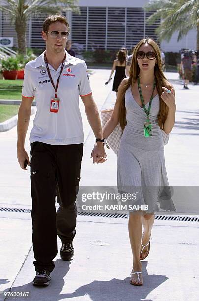 McLaren Mercedes' British driver Jenson Button and his girlfriend Jessica Michibata walk in the paddock of the Bahrain international circuit on March...
