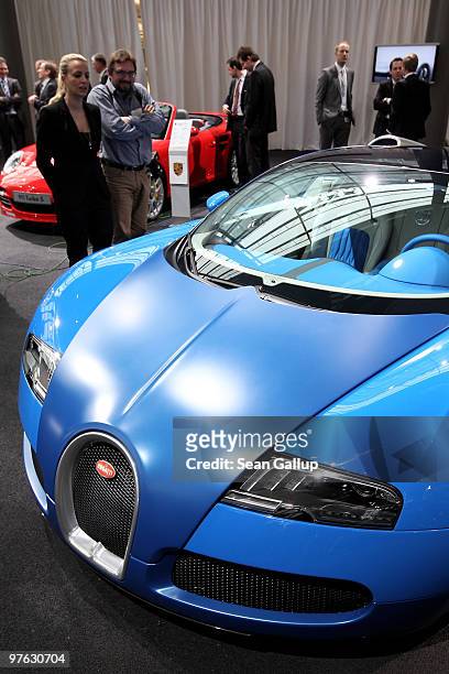 Journalists look at a Bugatti Veyron 16.4 Grand Sport, which retails at EUR 1 000 and as a brand belongs to Volkswagen, at VW's annual press...