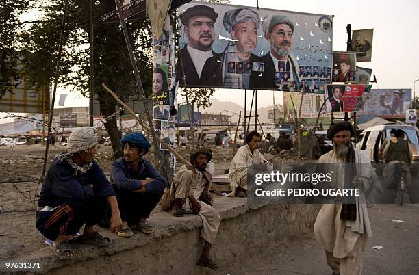 Afghans relax in a street displaying electoral banners in Kabul on August 17, 2009 during the last day of campaigning for key elections overshadowed...