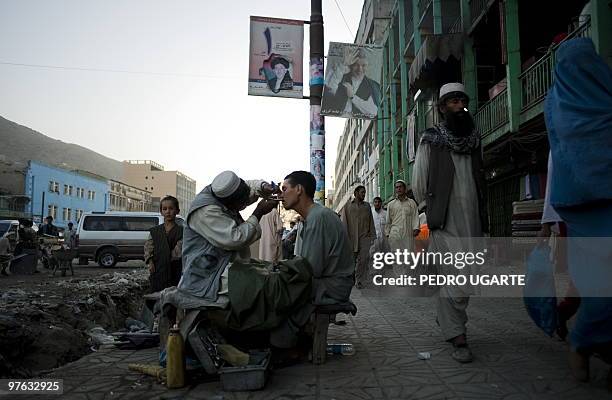 An Afghan street shaver works in a street of Kabul on August 11, 2009. Afghans vote next week to choose a president for only the second time in...