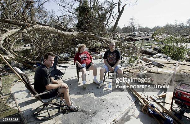 Jonh Swanson sits with his in-laws Kathy and Fran Green 30 August, 2005 on the slab that used to be their bedroom after their house in Biloxi,...