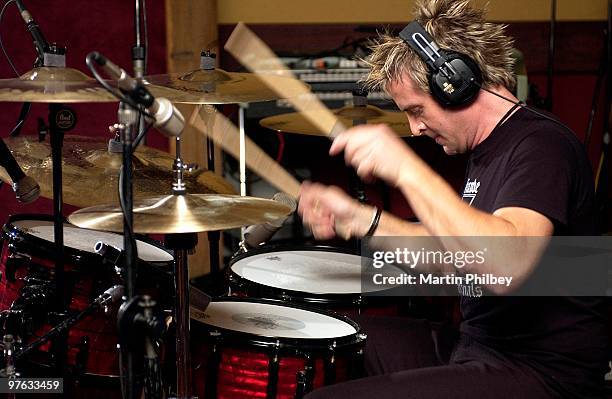 Andy Strachan of The Living End playing drums in a recording studio wearing headphones on 11th August 2004 in Melbourne, Australia.