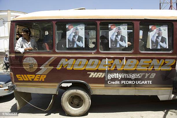 An Afghan man waits inside a bus adornated with posters of incumbent president Hamid Karzaiand after an electoral rally in Kabul on August 12, 2009....