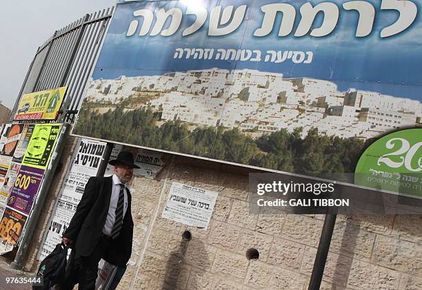 An Israeli ultra-Orthodox Jewish man walks past a sign with the image of the east Jerusalem settlement of Ramat Shlomo, on March 11, 2010. Israeli...