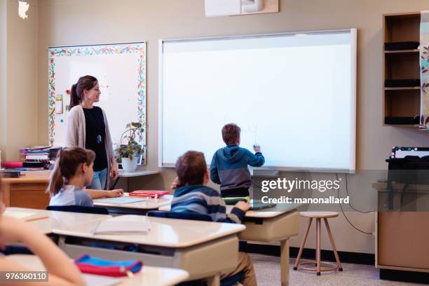 lezione di scrittura shcoolboy in lavagna interattiva in classe - interactive whiteboard foto e immagini stock