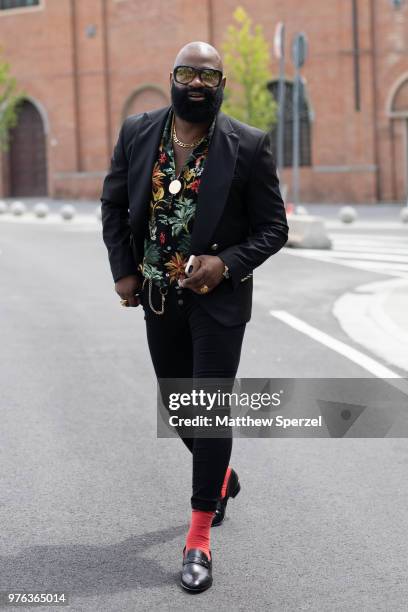 Guest is seen during the 94th Pitti Immagine Uomo wearing a black suit with floral shirt and orange socks on June 14, 2018 in Florence, Italy.