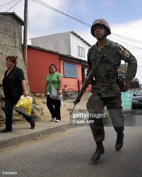 Soldier and residents of the coastal town of Constitucion, some 300 km from Santiago, head towards higher land, following a tsunami alert triggered...