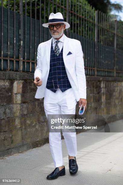 Guest is seen during the 94th Pitti Immagine Uomo wearing a white suit with plaid navy vest and white hat on June 14, 2018 in Florence, Italy.