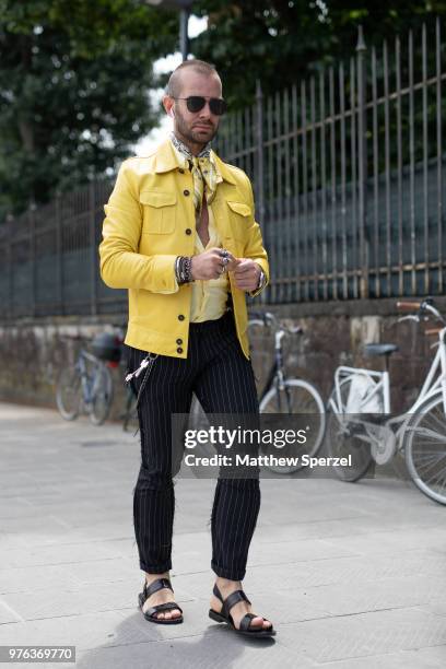 Guest is seen during the 94th Pitti Immagine Uomo wearing a yellow jacket with black stripe pants and sandals on June 14, 2018 in Florence, Italy.