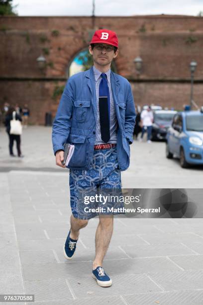 Guest is seen during the 94th Pitti Immagine Uomo wearing a blue coat with blue pattern shorts and red cap on June 14, 2018 in Florence, Italy.