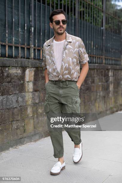 Guest is seen during the 94th Pitti Immagine Uomo wearing a copper pattern shirt with army green cargo pants and white shoes on June 14, 2018 in...