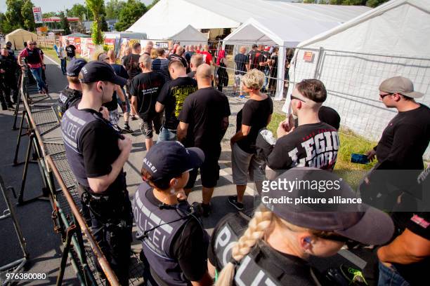 June 2018, Germany, Themar: Festivalgoers pass police officers at the entrance to the festival site at the "Tage der nationalen Bewegung" festival....
