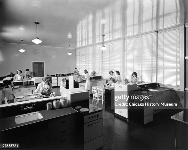 View of female student as they work at kitchen station in a home economics glass at Oak Ridge High School, Oak Ridge, Tennessee, July 12, 1944. The...