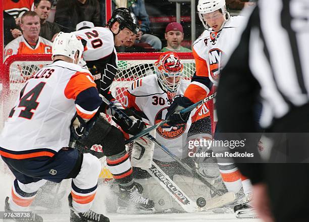 Chris Pronger of the Philadelphia Flyers attempts to slap the puck past Bruno Gervais and Dwayne Roloson of the New York Islanders on March 9, 2010...