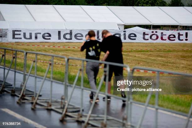 June 2018, Germany, Themar: Festivalgoers at the right-wing festival "Tage der nationalen Bewegung" walk past a banner that reads "Eure Ideologie...