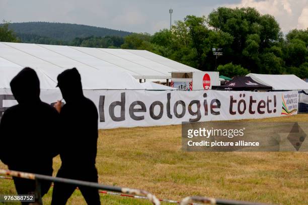 June 2018, Germany, Themar: Festivalgoers at the right-wing festival "Tage der nationalen Bewegung" walk past a banner that reads "Eure Ideologie...