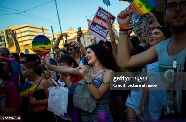 June 2018, Athens, Greece: Participants of the Gay Parade walk through the streets painted and dressed in vibrant colours, showcasing fans reading...