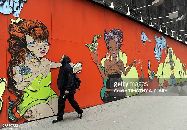 New Yorkers pass the mural by Puerto Rican artist Sofia Maldonado called "42nd Street Mural" March 11, 2010 drawn on the side of a construction fence...