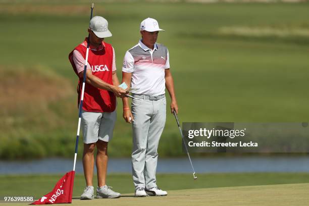 Rickie Fowler of the United States talks with his caddie Joseph Skovron on the sixth green during the third round of the 2018 U.S. Open at Shinnecock...