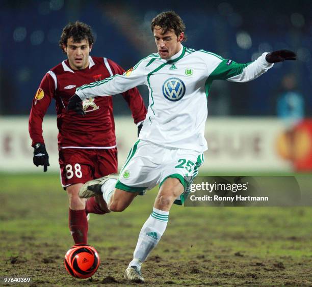 Christian Gentner of Wolfsburg and Alan Kasaev of Kazan battle for the ball during the UEFA Europa League round of 16 first leg match between Rubin...